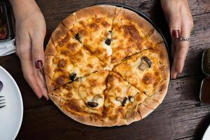 paddestoel pizza met een dun, taai Aan vrouw hand- foto