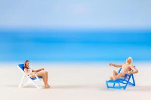 miniatuur mensen , paar ontspannende Aan strand stoelen Aan de strand foto