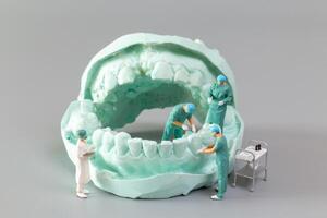 miniatuur mensen ,a tandarts weergeven tandheelkundig modellen en gips orthodontisch modellen foto