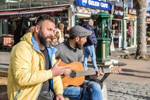 Istanbul, kalkoen - december 29, 2022. twee Heren, een spelen gitaar en zingen, de andere luisteren aandachtig Aan een stad straat hoek. foto