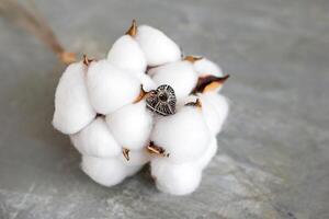 zilver ring Aan een wit katoen bloemen Aan een grijs achtergrond met kopiëren ruimte. handgemaakt kostbaar item. foto