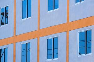 laag hoek en kant visie van blauw lucht reflectie Aan glas ramen oppervlakte van modern gebouw muur foto