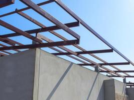metaal schuur dak framing structuur Aan beton huis muur in bouw plaats, laag hoek en perspectief visie foto