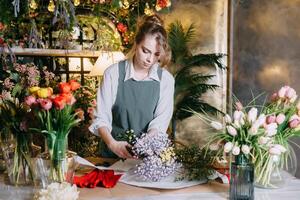 een vrouw in haar bloemist winkel verzamelt boeketten van bloemen. de concept van een klein bedrijf. boeketten van tulpen voor de vakantie Aan maart 8. foto
