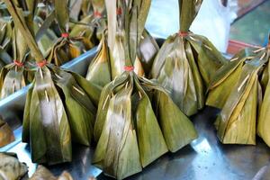 Thais toetje , gestoomd kokosnoot vla met zoet kokosnoot vulling in banaan blad pakket verkoop in Thailand straat markt foto