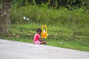sorong, west papua, indonesië, 10-31-21 meisje speelt aan de kant van de weg foto
