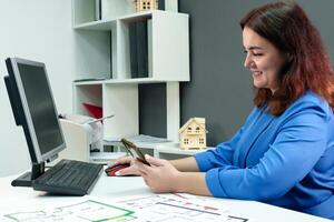 gekruld brunette in een blauw pak in een kantoor Bij een computer overbrengt een zin van ervaring en ambitie verwant naar professioneel groei foto