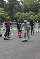 Indonesië - Medan, 22 juli 2023 groep van Aziatisch mensen skateboarden Aan de straat foto