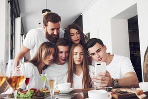 een groep mensen maakt een selfie-foto in een café. de beste vrienden verzamelden zich aan een eettafel, aten pizza en zongen verschillende drankjes foto