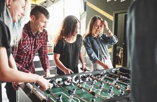 lachende jonge mensen die binnen tafelvoetbal spelen foto