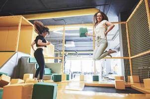 het bedrijf is een jonge vrouw die zich amuseert met zachte blokken op een kinderspeelplaats in een trampolinecentrum. foto