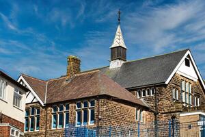 traditioneel steen school- gebouw met een spits tegen een blauw lucht met piekerig wolken in harrogeren, noorden yorkshire. foto