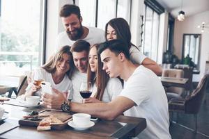 een groep mensen maakt een selfie-foto in een café. de beste vrienden verzamelden zich aan een eettafel, aten pizza en zongen verschillende drankjes foto