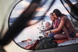 uitzicht vanuit tent van paar met kaart liggend op het meer tijdens wandeltocht. avel lifestyle concept avontuurlijke vakanties buiten foto