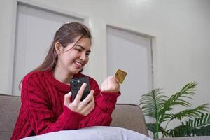 vrouw Holding credit kaart en gebruik makend van smartphone Bij huis, online winkelen, online bankieren, betaling, uitgeven geld, e-commerce Bij op te slaan, credit kaart concept foto