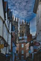 historisch Europese stadsgezicht met gotisch kathedraal torenhoog over- traditioneel gebouwen onder een dramatisch bewolkt lucht in york, noorden yorkshire, Engeland. foto