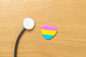 pansexueel trots dag en lgbt trots maand concept. roze, geel en blauw hart vorm met stethoscoop voor lesbienne, homo, biseksueel, transgender, vreemd en pansexueel gemeenschap foto