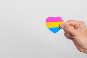 pansexueel trots dag en lgbt trots maand concept. hand- Holding roze, geel en blauw hart vorm voor lesbienne, homo, biseksueel, transgender, vreemd en pansexueel gemeenschap foto