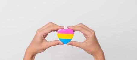 pansexueel trots dag en lgbt trots maand concept. hand- Holding roze, geel en blauw hart vorm voor lesbienne, homo, biseksueel, transgender, vreemd en pansexueel gemeenschap foto