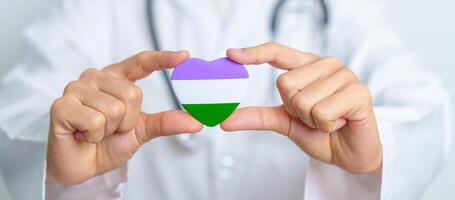 vreemd trots dag en lgbt trots maand concept. dokter hand- Holding Purper, wit en groen hart vorm met stethoscoop voor lesbienne, homo, biseksueel, transgender, genderqueer en pansexueel gemeenschap foto