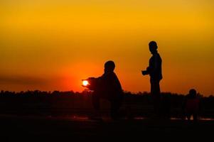 kindsilhouet speelplezier met veel vrienden en spelen tegen de zonsondergang foto