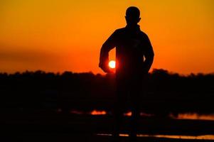 kindsilhouet speelplezier met veel vrienden en spelen tegen de zonsondergang foto