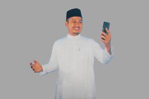 Moslim Aziatisch Mens glimlachen gelukkig terwijl op zoek naar zijn mobiel telefoon foto