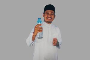 Moslim Aziatisch Mens glimlachen Bij de camera terwijl Holding een fles van drinken water foto