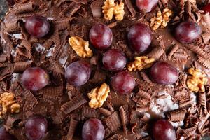 taart met chocola suikerglazuur en druiven dichtbij omhoog foto