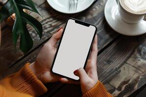 handen Holding telefoon met wit mockup scherm tegen koffie tafel backdrop foto