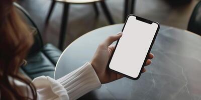 handen Holding telefoon met wit mockup scherm tegen koffie tafel backdrop foto