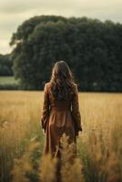 een vrouw in een bruin jurk staand in een veld- foto