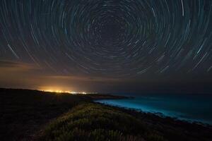 ster trails over- de oceaan Bij nacht foto