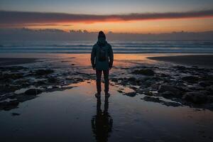 ai gegenereerd een persoon staand Aan de strand Bij zonsondergang foto