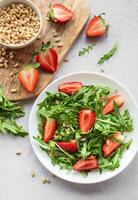 vers aardbei rucola salade met pijnboom noten geserveerd Aan een helder dag foto