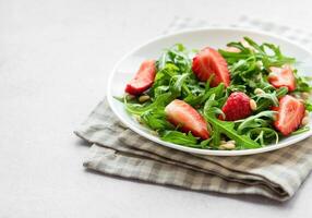 vers aardbei rucola salade met pijnboom noten geserveerd Aan een helder dag foto