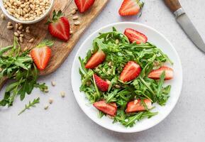 vers aardbei rucola salade met pijnboom noten geserveerd Aan een helder dag foto