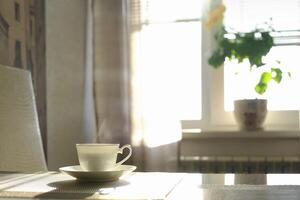 kop van heet stomen koffie Aan een zonnig ochtend- Aan de keuken tafel foto