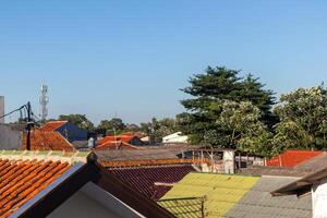 visie van tegel daken en bomen met Doorzichtig blauw lucht in een woon- Oppervlakte in de voorstad van Jakarta foto