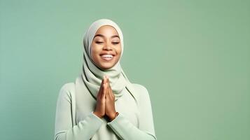 Afrikaanse vrouw vervelend sjaal is bidden en glimlachen Aan groen achtergrond foto