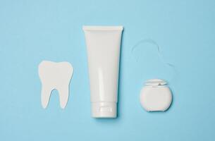 buis met tandpasta en tandheelkundig floss Aan een blauw achtergrond foto