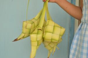 ketupat geïsoleerd Aan wit achtergrond. een typisch eid al-fitr schotel gemaakt van rijst- verpakt in een inpakken gemaakt van geweven jong kokosnoot bladeren. typisch Maleis en Indonesisch voedsel foto