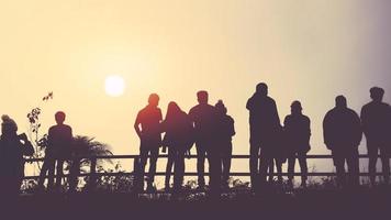 aziaten reizen ontspannen in de vakantie. mensen staan 's ochtends naar de zon te kijken. sta op voor zonsopgang op de berg foto