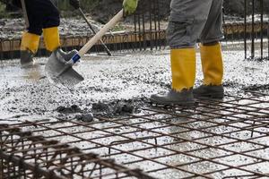 metselaars die het vers gestorte beton egaliseren om de fundamenten van een gebouw te leggen foto