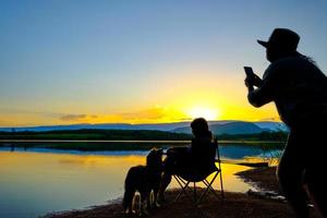 silhouetten van twee jonge vrouwen die een foto nemen over een grijze achtergrond op het meer bij zonsondergang