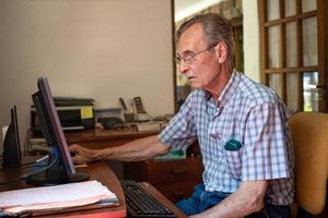 oudere man erg geconcentreerd achter de computer thuis, foto