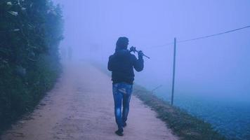 aziatische man fotograaf ontspannen in de vakantie. graag reizen in de vakantie. tijdens de mistige winter foto