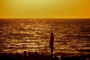 vrouw kijkt naar de zonsondergang in agaete port foto