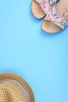 zomerschoenen en een strohoed op blauwe achtergrond. zomer concept achtergrond met plas voor tekst foto