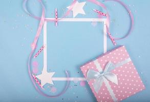 feestvakantie achtergrond met lint, sterren, verjaardagskaarsen, geschenkdoos leeg frame en confetti op blauwe achtergrond. foto